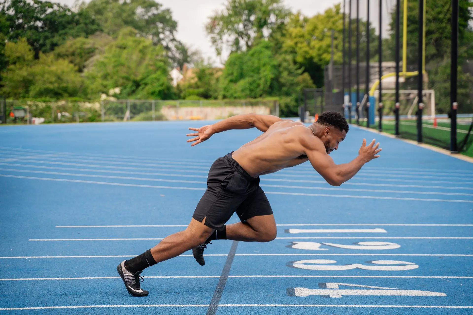 Un athlète s’élance sur une piste d’athlétisme bleue